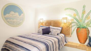 Une chambre à coucher avec un lit, un tableau rond représentant des nuages et un oiseau, une grande plante en pot et une tête de lit en osier.