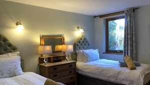 Une chambre d’hôtel avec deux lits, une commode, un miroir et deux appliques murales.