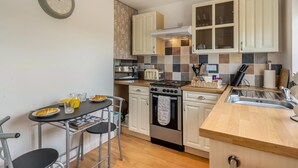 A compact kitchen with a stove, oven, and a small dining area with a table and chairs. - 1 Bed in Apley (oc-l32084) (Apley)