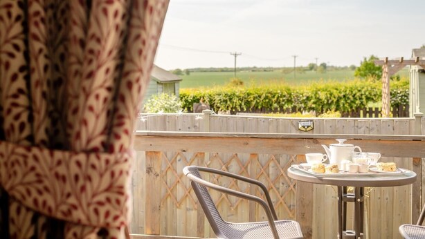 A patio with a table set for tea, a chair, and a view of a vineyard. - 1 Bed in Apley (oc-l32084) (Apley)