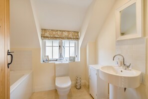 A bathroom with a bathtub, toilet, sink, and a window with a floral valance. - 3 Bed in West Lulworth (oc-s32114) (West Lulworth)