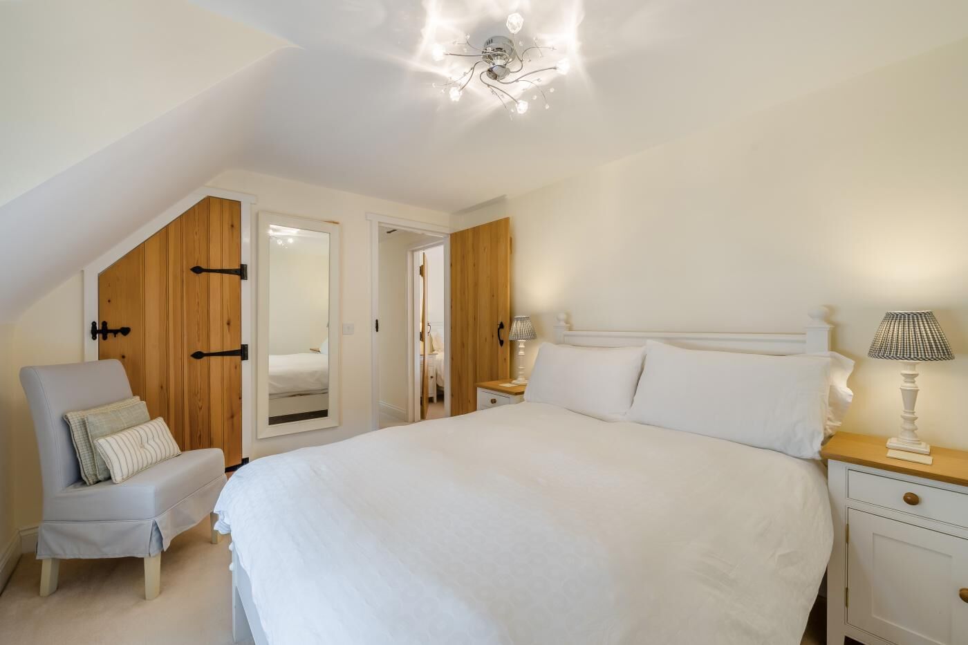 A bedroom with a large bed, a chair, a nightstand, and a ceiling light fixture.