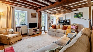 A cozy living room with a television, sofa, and piano. - 4 Bed in Sudbourne (oc-w32267) (Sudbourne)
