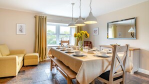 A dining area with a table set for four, a bench, a sofa, and a window with curtains.