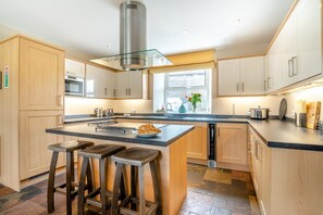 A modern kitchen with a central island, bar stools, and a window providing natural light.