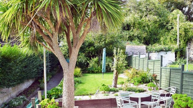 Un jardin avec un arbre, une table et des chaises.