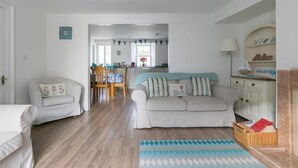 Un salon confortable avec un canapé, une table à manger et des chaises, et un coin cuisine en arrière-plan.