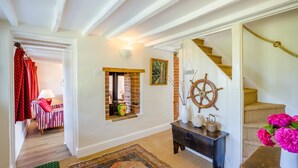 A hallway with a staircase, a ship's wheel decoration, a vase with flowers, and a patterned rug. - 3 Bed in Lower Holbrook (oc-2aglh) (Lower Holbrook)