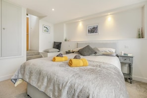 A bedroom with a bed, two bedside tables, a nightstand, a chair, a staircase, and two framed pictures on the wall. - 2 Bed in Marazion (oc-smccsh) (Marazion)