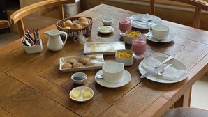 A wooden dining table set with breakfast items including bread, butter, and beverages.