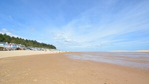 A beach with a row of beach huts and a clear sky. - 4 Bed in Wells-next-the-Sea (oc-2045) (Wells-next-the-Sea)
