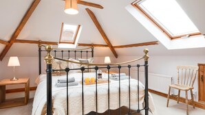A bedroom with a four-poster bed, skylights, a wooden chair, and a bedside table with a lamp. - 4 Bed in Wells-next-the-Sea (oc-2045) (Wells-next-the-Sea)