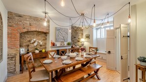 Un espace repas avec un mur en briques, une table en bois et des luminaires suspendus.
