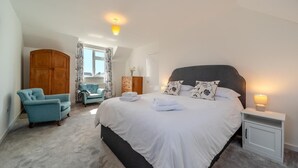 A bedroom with a large bed, a nightstand, a wardrobe, a chair, and a window with curtains. - 3 Bed in Clachan (oc-h32242) (Clachan)