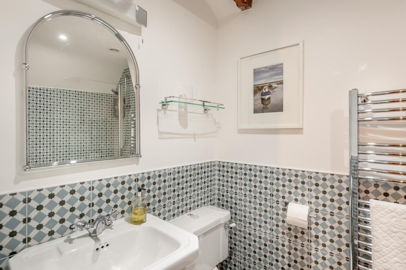 A bathroom with a sink, mirror, toilet, and a shower area.