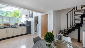 Une cuisine moderne avec un coin repas, un escalier et une vue sur l’extérieur.