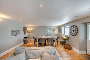 A dining area with a table set for four, a sofa in the foreground, and a wall clock. - 2 Bed in Barbon (oc-b32217) (Barbon)