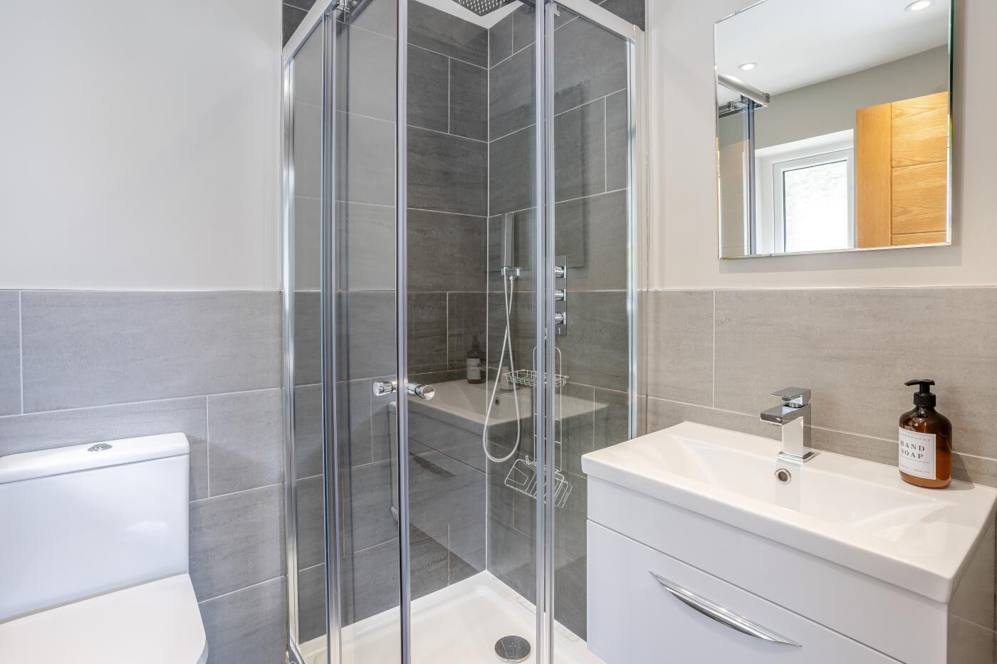 A modern bathroom with a glass-enclosed shower, a white sink, and a mirror above the vanity.