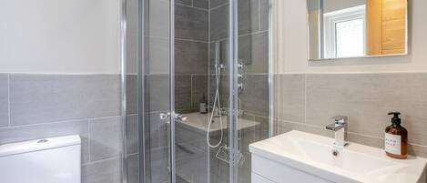 A modern bathroom with a glass-enclosed shower, a white sink, and a mirror above the vanity.