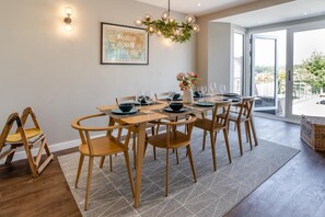 A dining area with a table set for four, wooden chairs, a hanging light fixture, and a framed map on the wall. - 4 Bed in Mumbles (oc-t32236) (The Mumbles)
