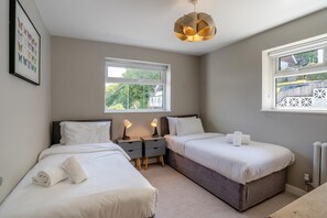 A bedroom with two beds, a nightstand, a window, and a ceiling light fixture. - 4 Bed in Mumbles (oc-t32236) (The Mumbles)