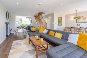 A spacious living area with a grey sectional sofa, wooden coffee table, and a staircase leading to an upper level. - 4 Bed in Mumbles (oc-t32236) (The Mumbles)