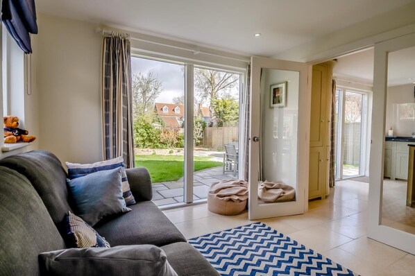 A living room with a sofa, a rug, and a sliding glass door leading to a patio. - 4 Bed in Walberswick (oc-pemb) (Walberswick)