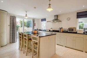 A modern kitchen with a central island, bar stools, a microwave, toaster, and a kettle. - 4 Bed in Walberswick (oc-pemb) (Walberswick)