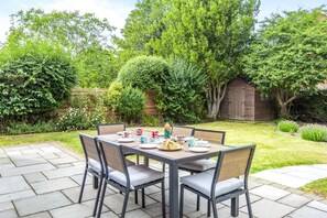An outdoor patio with a wooden table set for four, surrounded by chairs. - 4 Bed in Walberswick (oc-pemb) (Walberswick)