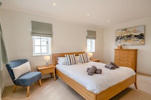Ein Schlafzimmer mit Bett, Sessel, Nachttisch, Kommode und einem Bild an der Wand.