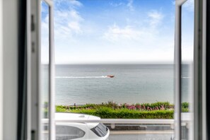 A view of the ocean from a window with a boat in the distance.