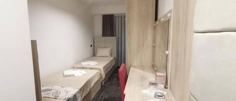 Een hotelkamer met twee enkele bedden, een kaptafel met spiegel en een klein zithoekje.