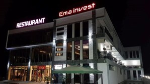 Un edificio de varios pisos con un restaurante llamado 'Ema Invest' en la planta baja.