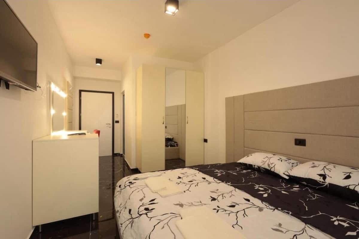 Una camera d'albergo con un letto, un comodino, uno specchio e un armadio.