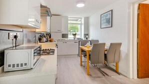 Une cuisine moderne équipée d’une cuisinière à gaz, d’un évier et d’un coin repas avec une table et des chaises.