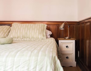 A bed with a striped bedspread and pillows, a bedside lamp, and a nightstand with drawers.