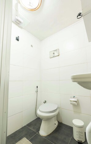 A small, white bathroom with a toilet, a shower, and a sink.
