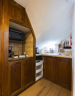A kitchen with wooden cabinets, a microwave, a coffee maker, and a sink.