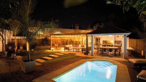A backyard with a swimming pool, outdoor seating, and a covered patio area.