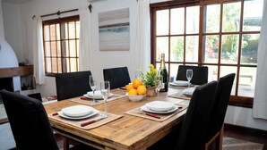 A dining table set for six with plates, glasses, and a centerpiece of oranges and flowers.