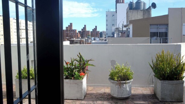 Eine Dachterrasse mit Topfpflanzen und Blick auf die Stadt.