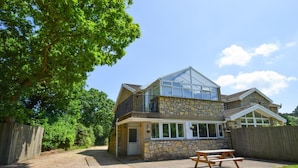 A two-story stone house with a large glass conservatory, a wooden deck, and a picnic table. - 2 Bed in Cardiff (oc-45378) (Gwern-y-Steeple)