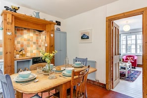 Un coin repas avec une table en bois, des chaises et un vase de fleurs. Il y a également un coin cuisine avec une cuisinière et des placards.