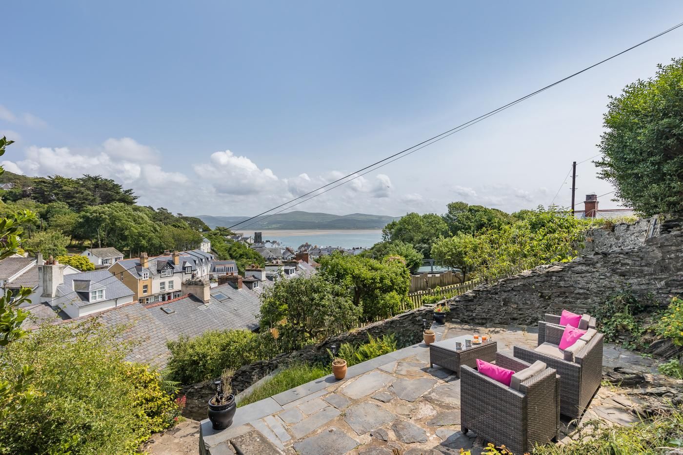A coastal town with stone buildings, a stone wall, and a view of the sea.