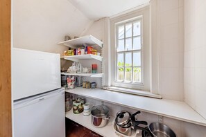A compact kitchen with white cabinetry, a built-in window, and a refrigerator.