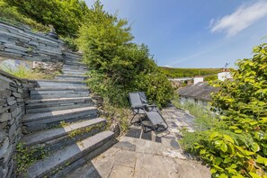 A stone staircase leading to a patio with a lounge chair.