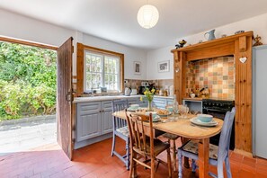 Une cuisine équipée d’une table à manger, de chaises, d’une cuisinière et d’une fenêtre.