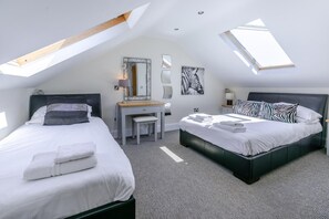 A bedroom with two beds, a desk, a mirror, and artwork on the walls.