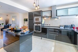 A modern kitchen with a central island, built-in appliances, and a dining area with a table and chairs.