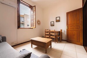 A room with a wooden table, chairs, a sofa, a window, and a door.